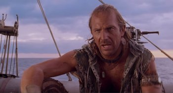 Movie still from “Waterworld” (1995), directed by Kevin Reynolds – A person sitting on a boat in the water; Close Up shot, Low angle