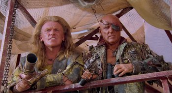 Movie still from “Waterworld” (1995), directed by Kevin Reynolds – A couple of men standing next to each other on a bridge; Medium shot, Low angle