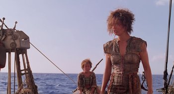 Movie still from “Waterworld” (1995), directed by Kevin Reynolds – A woman and a child are on a boat in the ocean; Medium shot, Low angle