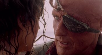 Movie still from “Waterworld” (1995), directed by Kevin Reynolds – A person wearing a pair of sunglasses; Close Up shot, Over the shoulder angle