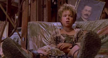 Movie still from “Waterworld” (1995), directed by Kevin Reynolds – A young child sitting on a couch in a room; Medium shot, Low angle