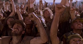 Movie still from “Waterworld” (1995), directed by Kevin Reynolds – A group of people in a crowd raising their hands; Medium shot, Low angle