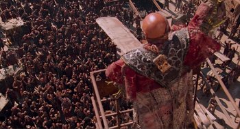 Movie still from “Waterworld” (1995), directed by Kevin Reynolds – A crowd of people standing around a building; Extreme Wide shot, Overhead angle