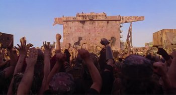 Movie still from “Waterworld” (1995), directed by Kevin Reynolds – A group of people standing in front of a building; Wide shot, Low angle