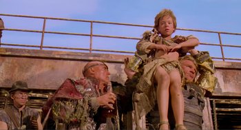 Movie still from “Waterworld” (1995), directed by Kevin Reynolds – A man and a woman sitting on a railing; Medium shot, Low angle