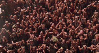Movie still from “Waterworld” (1995), directed by Kevin Reynolds – A large group of people with fists in the air; Wide shot, High angle