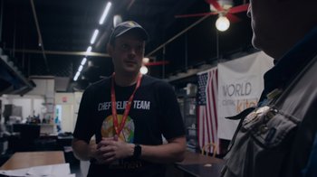 Movie still from “We Feed People” (2022), directed by Ron Howard – A man in a black shirt is standing in a room; Medium shot, Over the shoulder angle