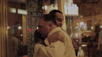 Movie still from “We Feed People” (2022), directed by Ron Howard – A couple of people that are hugging in a room; Close Up shot, Low angle