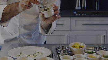 Movie still from “We Feed People” (2022), directed by Ron Howard – A person in a kitchen holding a bowl of food; Extreme Close Up shot, High angle