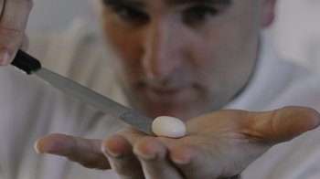 Movie still from “We Feed People” (2022), directed by Ron Howard – A man holding a knife and a small white object; Extreme Close Up shot, Low angle