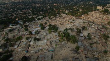 Movie still from “We Feed People” (2022), directed by Ron Howard – An aerial view of an urban area with a lot of rubble; Extreme Wide shot, High angle