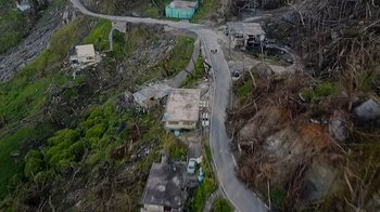 Movie still from “We Feed People” (2022), directed by Ron Howard – An aerial view of a road and houses in the middle of a destroyed area; Extreme Wide shot, Overhead angle