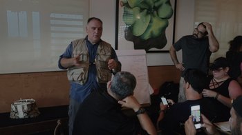 Movie still from “We Feed People” (2022), directed by Ron Howard – A man standing in front of a group of people; Medium shot, Over the shoulder angle