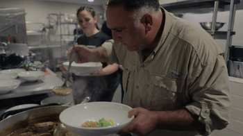Movie still from “We Feed People” (2022), directed by Ron Howard – A man holding a bowl of food in front of a woman; Close Up shot, Low angle