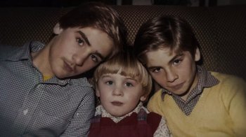 Movie still from “We Feed People” (2022), directed by Ron Howard – Three young boys sitting next to each other on a couch; Close Up shot, High angle