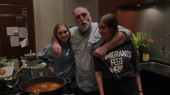 Movie still from “We Feed People” (2022), directed by Ron Howard – A man and two women posing for a picture in front of a pot of soup; Medium shot, Low angle