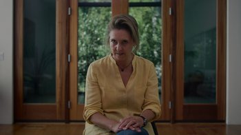 Movie still from “We Feed People” (2022), directed by Ron Howard – A woman sitting in a chair in front of a window; Medium shot, Low angle