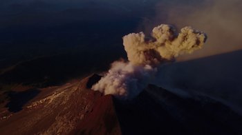 Movie still from “We Feed People” (2022), directed by Ron Howard – A very large plume of smoke coming out of a volcano; Extreme Wide shot, Overhead angle