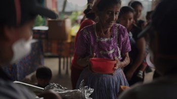 Movie still from “We Feed People” (2022), directed by Ron Howard – An older woman is holding a bowl in her hands; Medium shot, High angle