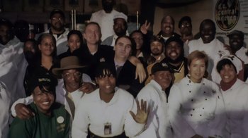 Movie still from “We Feed People” (2022), directed by Ron Howard – A group of people posing for a picture in a restaurant; Medium shot, High angle
