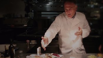 Movie still from “We Feed People” (2022), directed by Ron Howard – A man in a white lab coat is reaching for some food; Close Up shot, Low angle