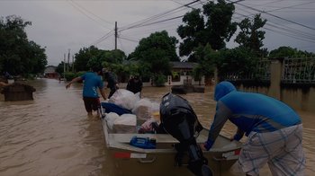 Movie still from “We Feed People” (2022), directed by Ron Howard – A group of people in a boat in a flooded area; Extreme Wide shot, High angle
