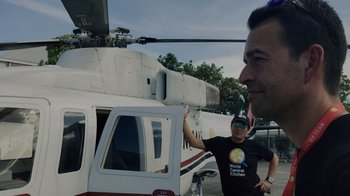 Movie still from “We Feed People” (2022), directed by Ron Howard – Two men standing in front of a helicopter; Medium shot, Low angle