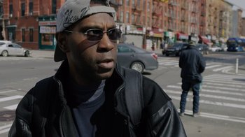 Movie still from “We Feed People” (2022), directed by Ron Howard – A man wearing sunglasses and a baseball cap; Close Up shot, Over the shoulder angle