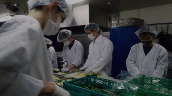 Movie still from “We Feed People” (2022), directed by Ron Howard – A group of people in a kitchen preparing food; Medium shot, Low angle