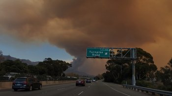 Movie still from “We Feed People” (2022), directed by Ron Howard – Cars driving on a highway under a cloudy sky; Extreme Wide shot, Low angle