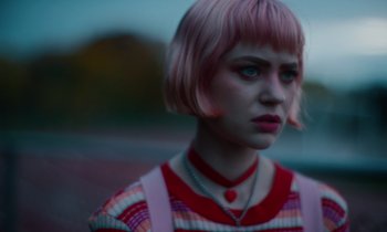 A woman with pink hair is looking into the distance