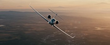 An airplane is flying in the air at sunset