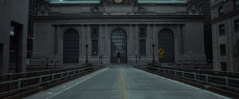 A person standing on the side of a road near a building