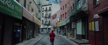 A woman in a red coat is walking down a street