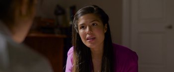 Movie still from “Wedding Season” (2022), directed by Tom Dey – A woman with long black hair wearing a pink shirt; Close Up shot, Over the shoulder angle