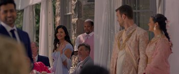 Movie still from “Wedding Season” (2022), directed by Tom Dey – A group of people standing next to each other on a stage; Medium shot, Over the shoulder angle