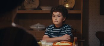 Movie still from “Weird: The Al Yankovic Story” (2022), directed by Eric Appel – A boy sitting at a table with a plate of food; Close Up shot, Over the shoulder angle