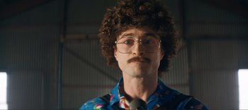 Movie still from “Weird: The Al Yankovic Story” (2022), directed by Eric Appel – A man with a curly hair and a mustache; Close Up shot, Over the shoulder angle