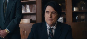 Movie still from “Weird: The Al Yankovic Story” (2022), directed by Eric Appel – A man in a suit and tie sitting at a table; Medium shot, Over the shoulder angle