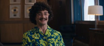 Movie still from “Weird: The Al Yankovic Story” (2022), directed by Eric Appel – A man in a blue and yellow shirt with a mustache; Medium shot, Over the shoulder angle