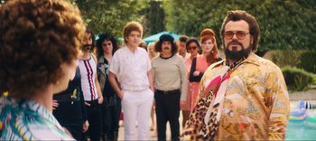 Movie still from “Weird: The Al Yankovic Story” (2022), directed by Eric Appel – A group of people standing in front of each other on a sidewalk; Wide shot, Over the shoulder angle