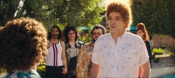 Movie still from “Weird: The Al Yankovic Story” (2022), directed by Eric Appel – A group of people standing next to each other near a tree; Medium shot, Over the shoulder angle