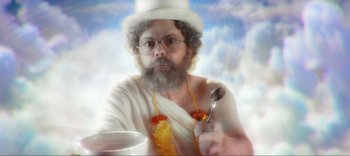 Movie still from “Weird: The Al Yankovic Story” (2022), directed by Eric Appel – A man with a beard and a white hat is holding a spoon; Medium shot, Low angle