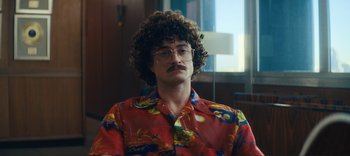 Movie still from “Weird: The Al Yankovic Story” (2022), directed by Eric Appel – A man with curly brown hair wearing a red hawaiian shirt; Close Up shot, Low angle