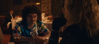 Movie still from “Weird: The Al Yankovic Story” (2022), directed by Eric Appel – Two people sitting at a table with wine glasses; Medium shot, Over the shoulder angle
