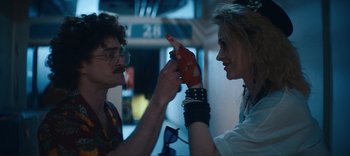Movie still from “Weird: The Al Yankovic Story” (2022), directed by Eric Appel – A man and a woman are touching each other's hands; Close Up shot, Over the shoulder angle