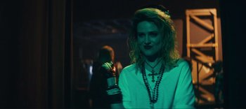 Movie still from “Weird: The Al Yankovic Story” (2022), directed by Eric Appel – A woman in a white shirt is holding a drink; Close Up shot, Over the shoulder angle