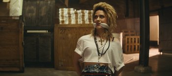 Movie still from “Weird: The Al Yankovic Story” (2022), directed by Eric Appel – A woman with a fake mustache on her mouth; Medium shot, Over the shoulder angle