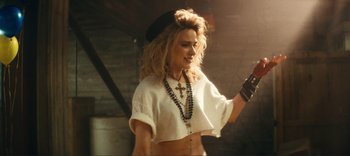 Movie still from “Weird: The Al Yankovic Story” (2022), directed by Eric Appel – A woman in a white shirt and a black hat; Medium shot, Over the shoulder angle