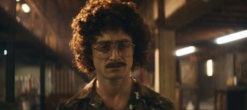 Movie still from “Weird: The Al Yankovic Story” (2022), directed by Eric Appel – A man with glasses and a curly hair wig; Close Up shot, Over the shoulder angle
